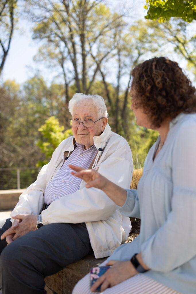 A Holocaust survivor sitting with caretaker.